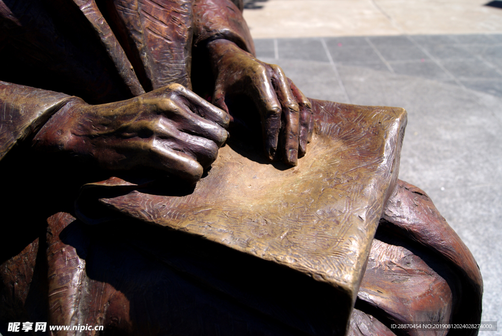 坐与书的妇女的古铜色雕象