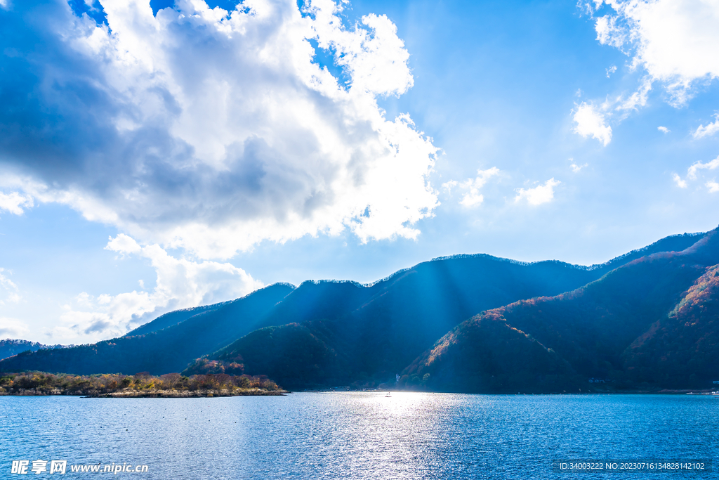 太阳透过云层洒向山边的湖泊