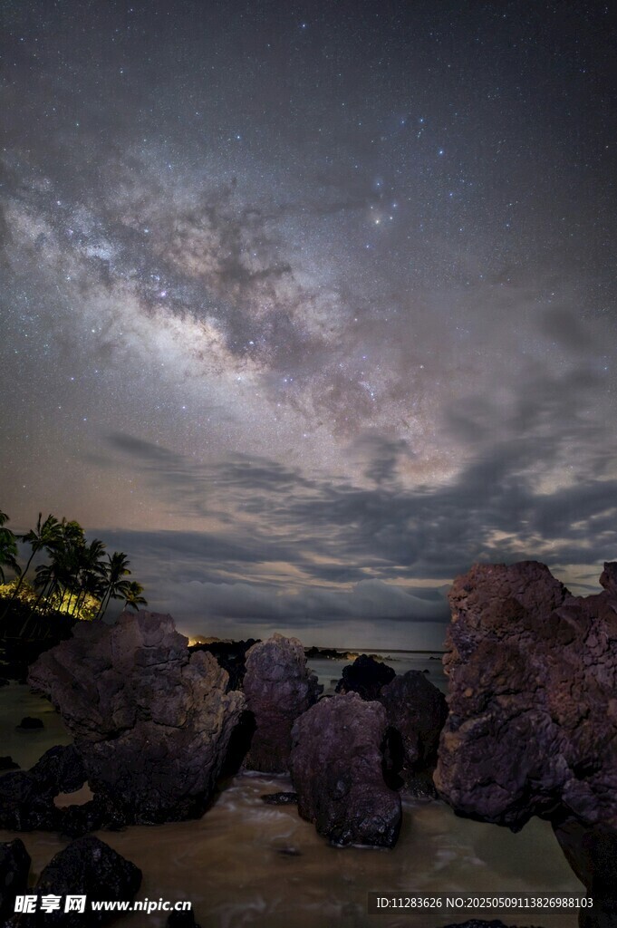海邊夜空下的巖石與星云