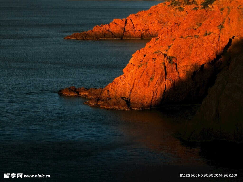 夕陽下的海邊紅色崖壁