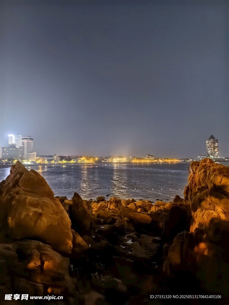 海邊夜景巖石與城市燈火