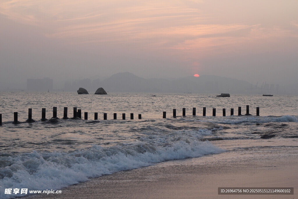 海邊日落時的海浪與木樁