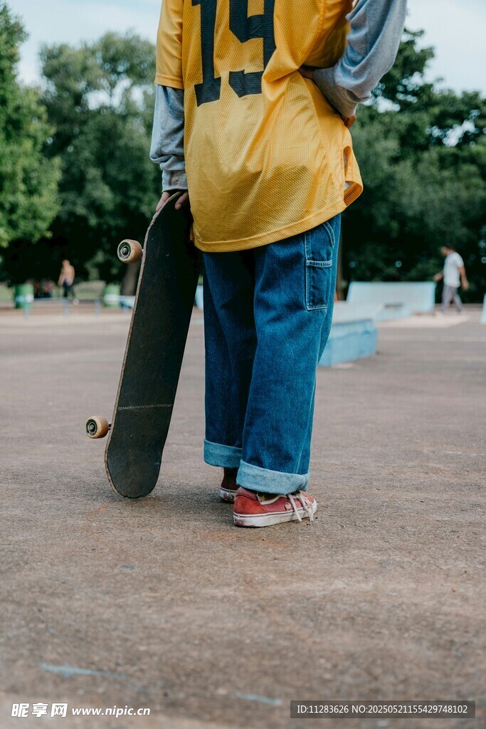 穿黃衣持滑板的少年背影