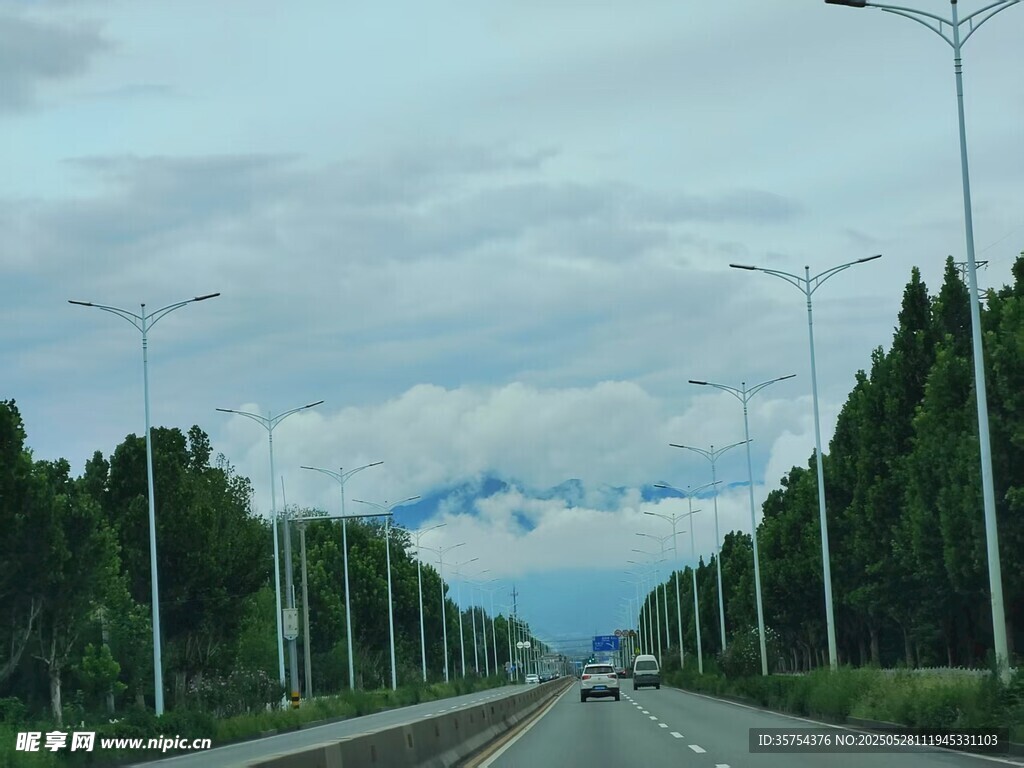 寬闊公路旁綠樹與遠山