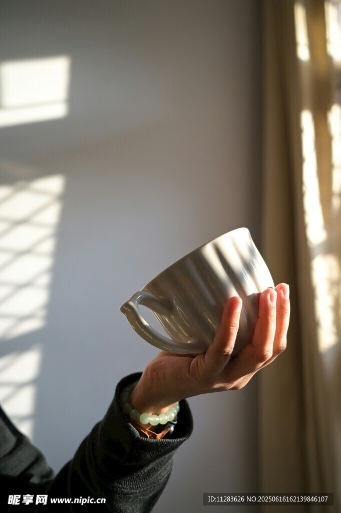 手托條紋杯于光影中