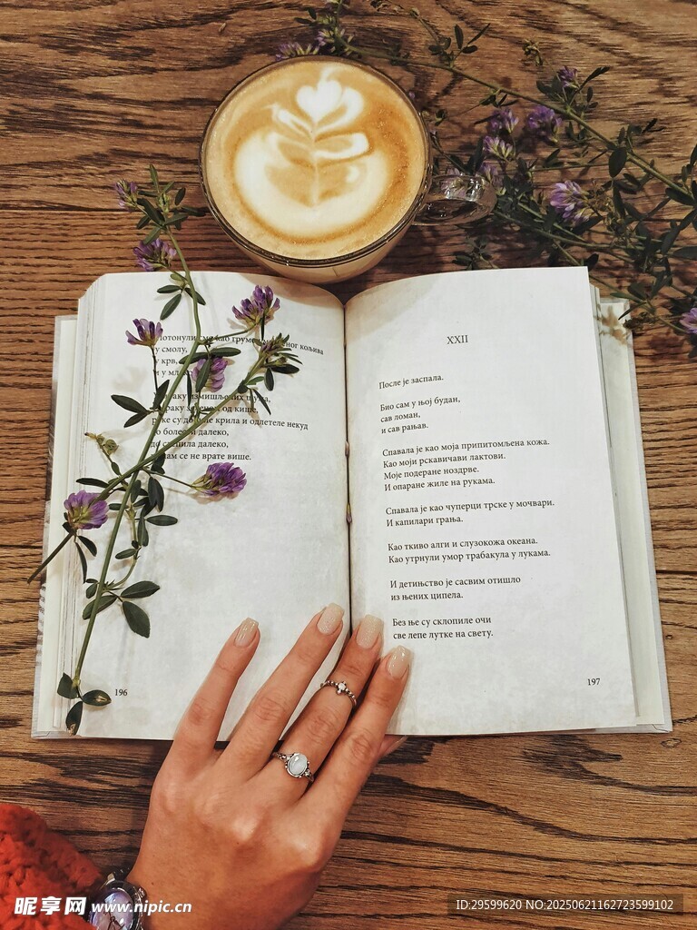 手撫書卷旁的咖啡與花枝