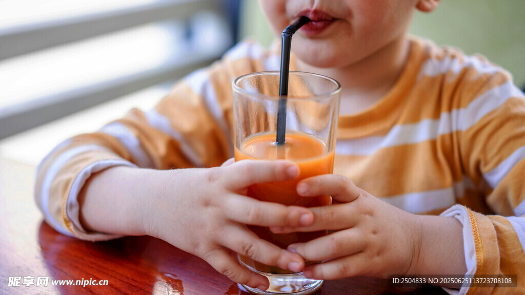 小孩手持吸管喝橙色飲品