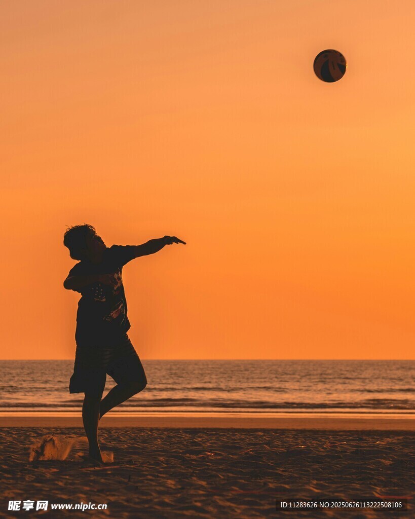 夕陽下海邊踢足球的身影