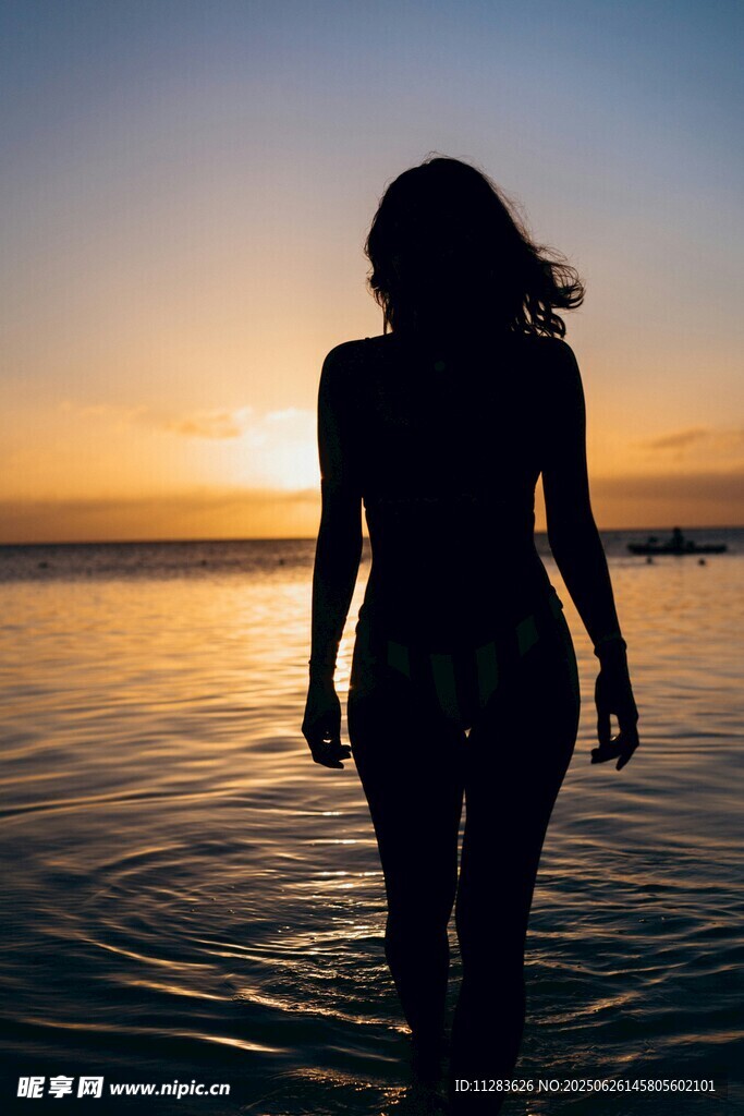 夕陽(yáng)下海邊漫步的女性身影