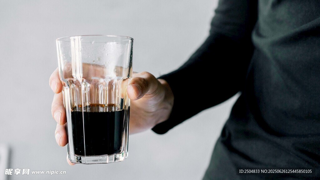 手持玻璃杯中的深色飲品