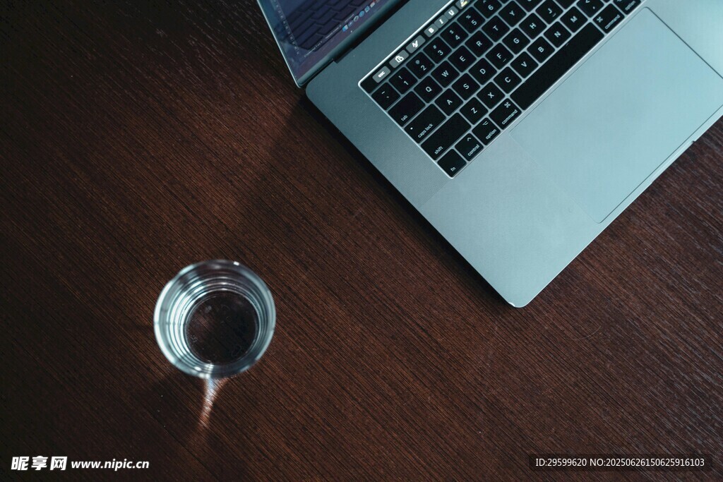 桌上筆記本電腦與玻璃杯
