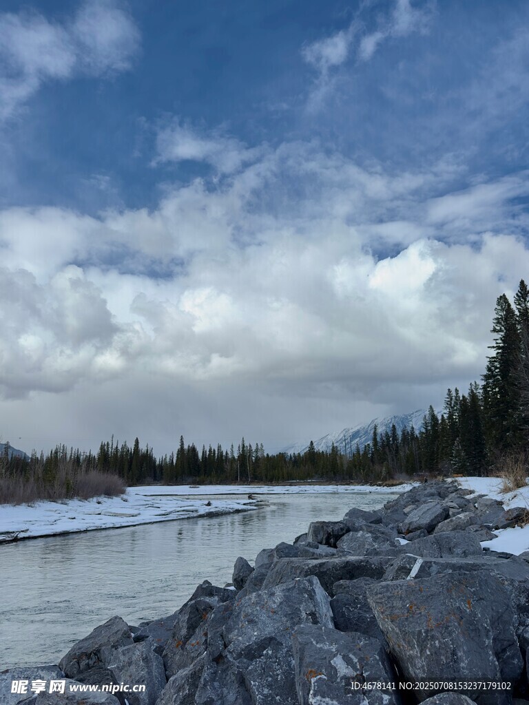 河畔雪景中的巖石與樹林