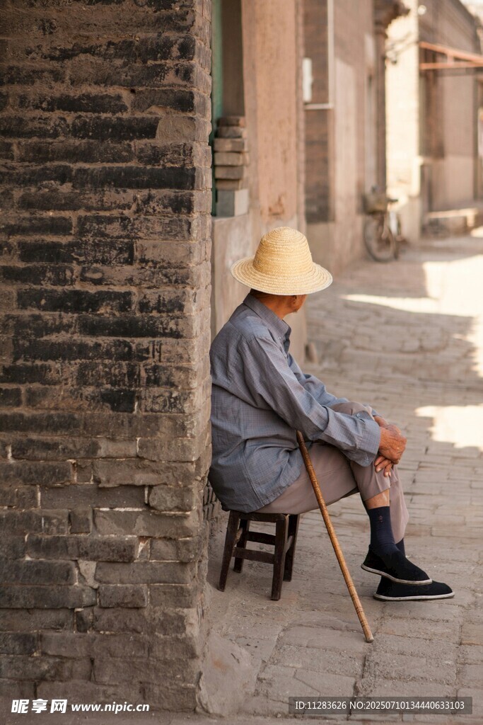 老人坐于古巷墻邊休憩
