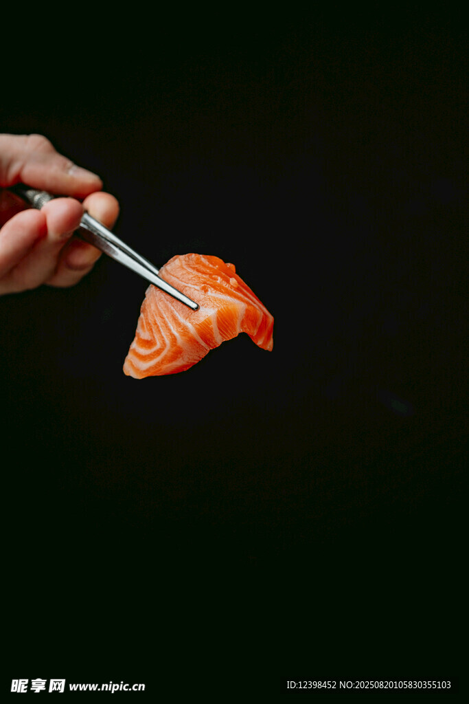 手持銀筷夾起三文魚