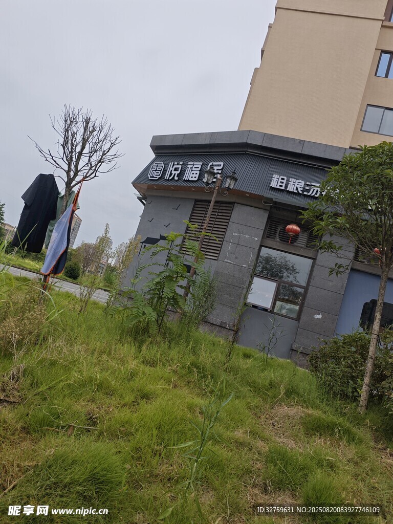 荒廢小屋立于草地與建筑間