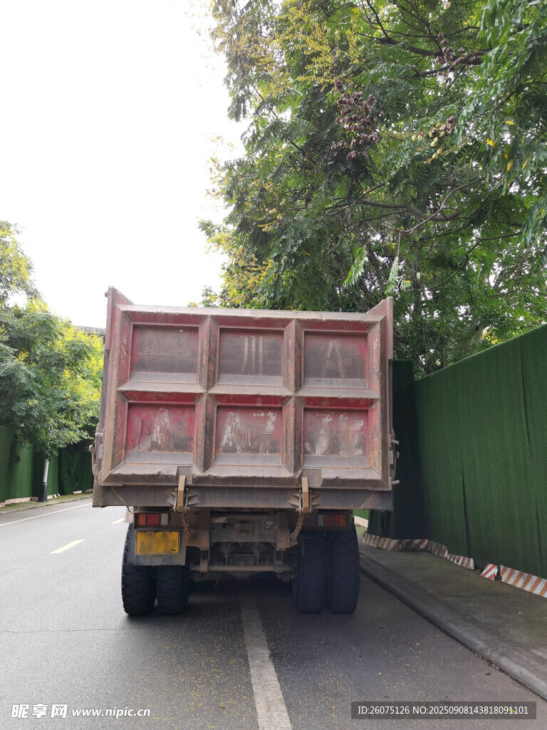 路邊停放的紅色自卸貨車尾部