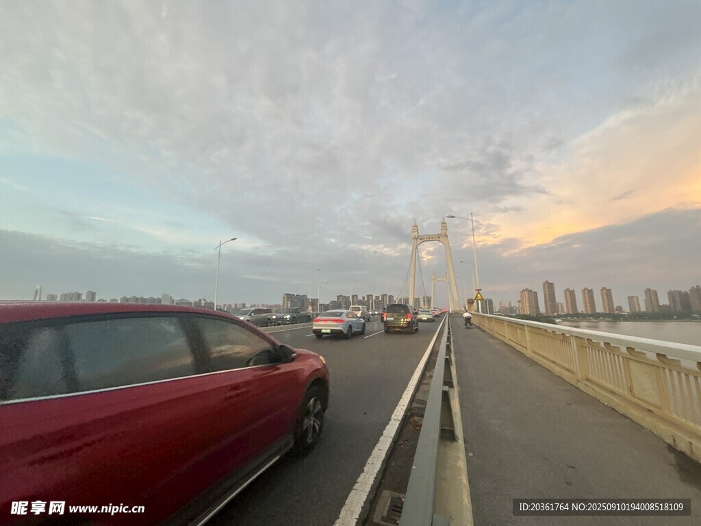 黃昏時橋上行駛的紅色汽車