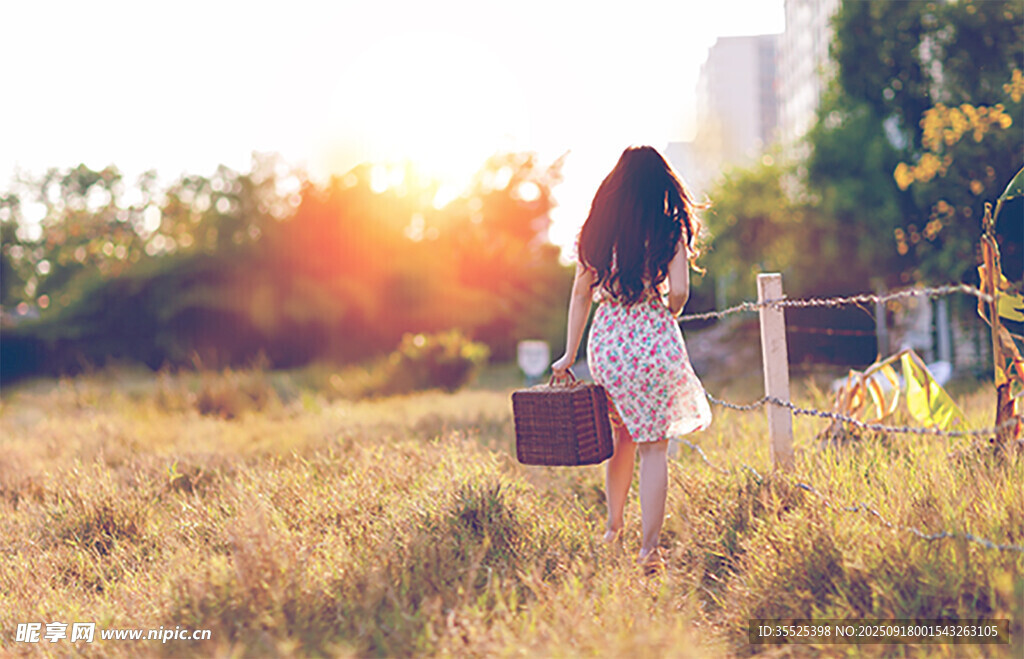 夕陽(yáng)下女孩提籃漫步草地