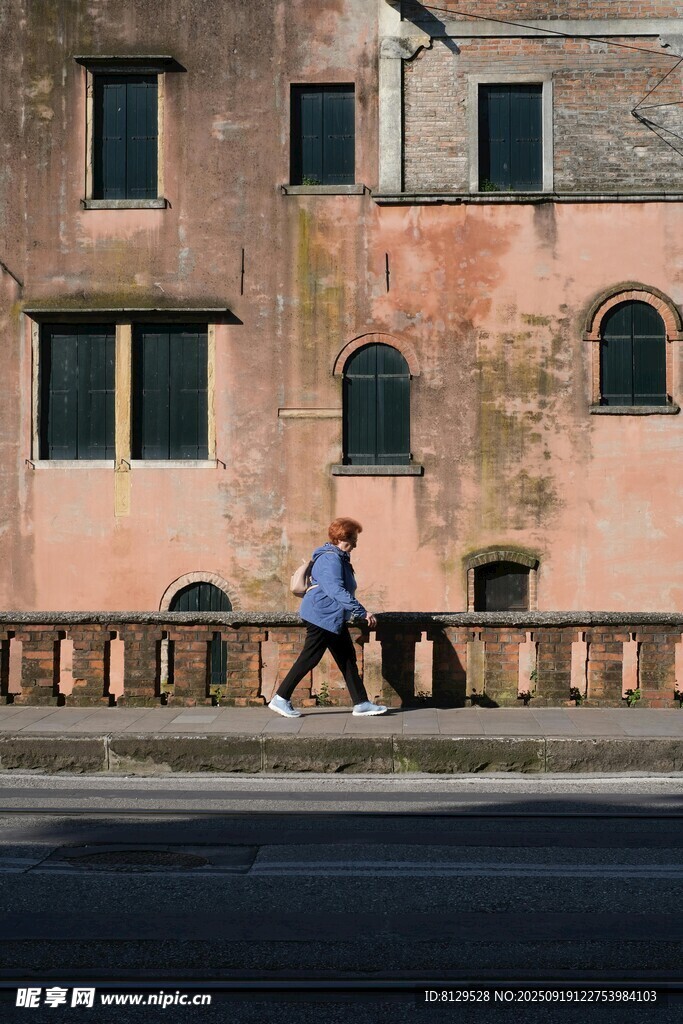 行人沿古老建筑旁道路行走