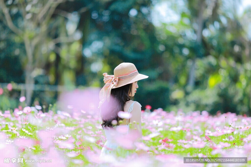 花海中戴草帽的女子背影
