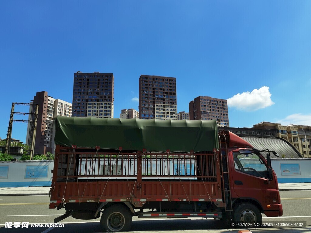 紅色貨車行駛于城市背景下