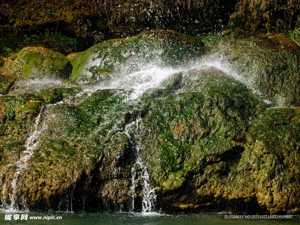 山間瀑布下的翠綠巖石