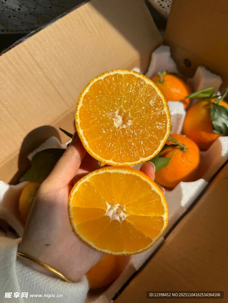 手捧切開橙子與箱中鮮果