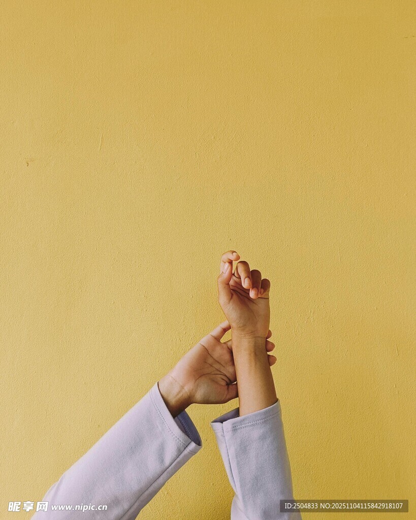 雙手交握于黃色背景前