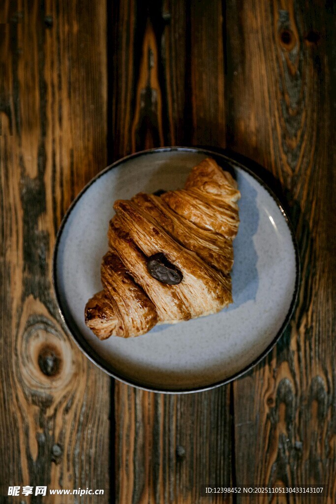 木桌上盤子里的美味牛角包