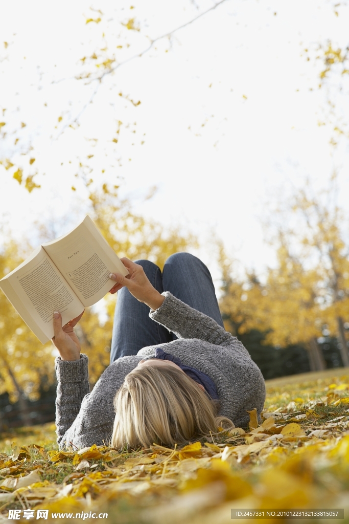 躺在秋天落叶上看书的女孩