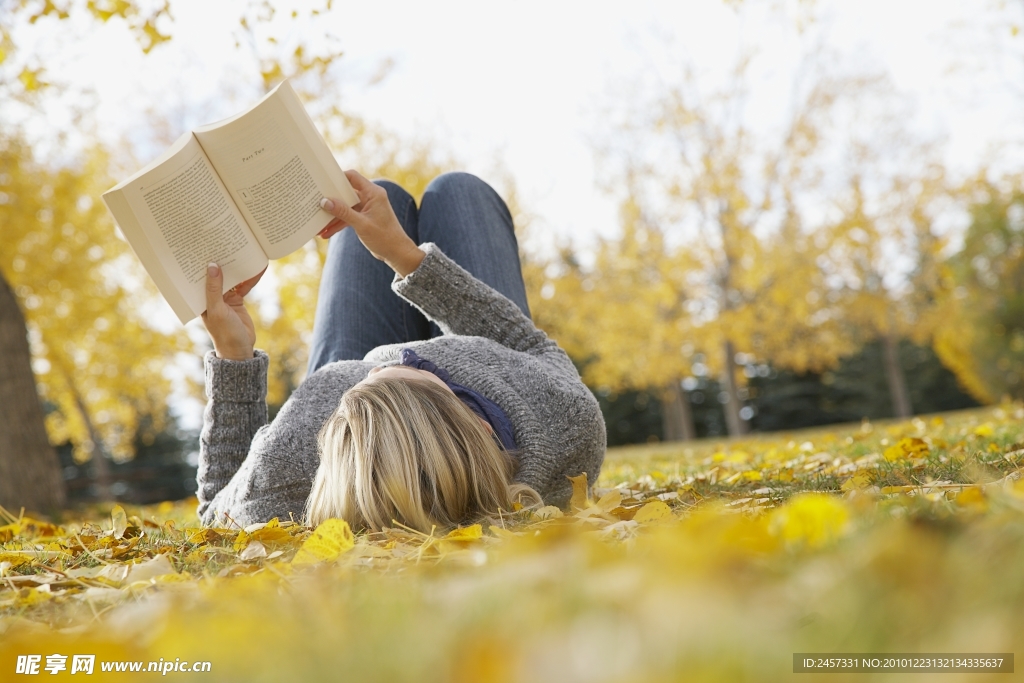 躺在秋天落叶上看书的女孩