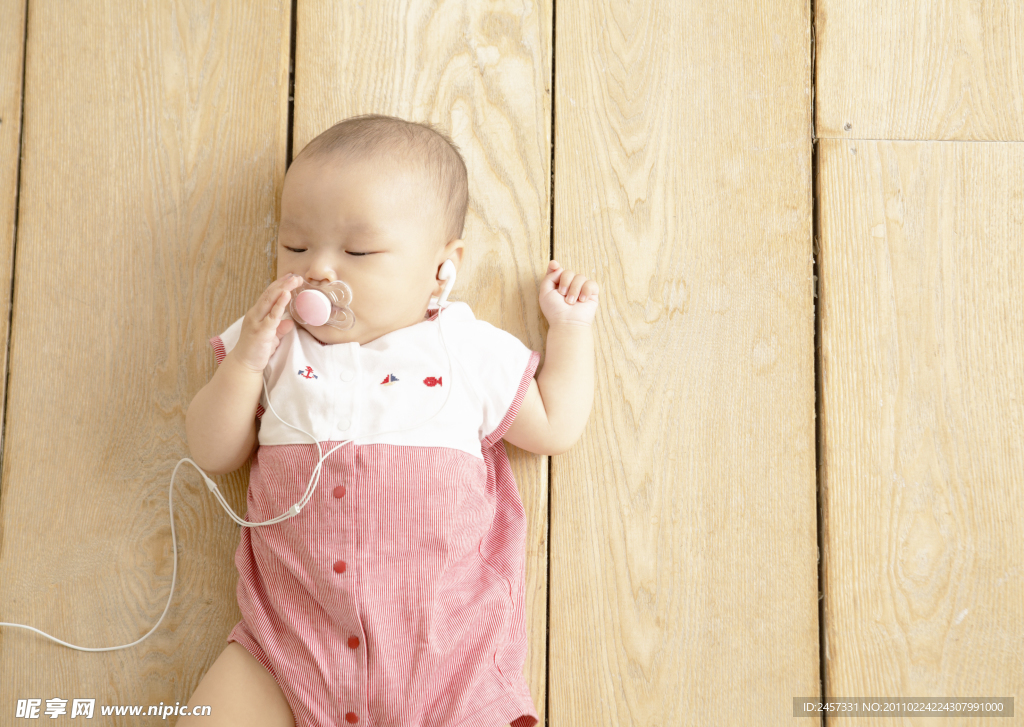 躺在木纹地板上听音乐的婴儿宝宝