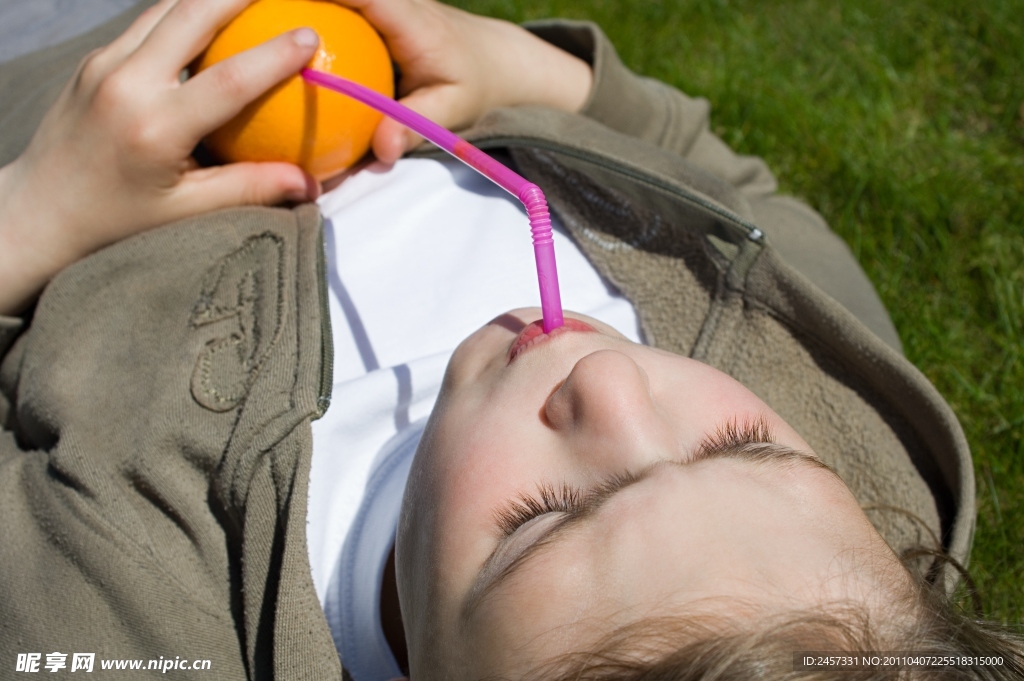 躺在草地上喝橘子汁的孩子