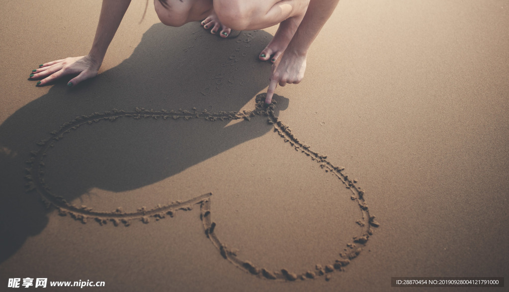 画在沙子的一个少妇的手心脏