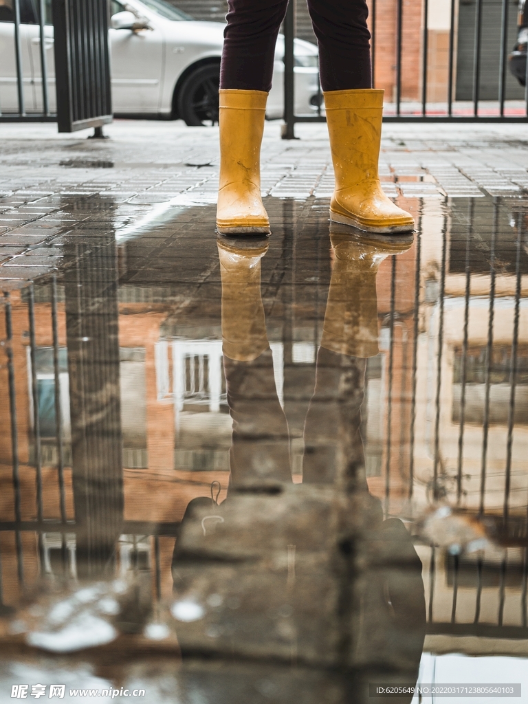 穿黄色雨鞋站在地面积水上