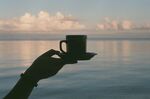 海边手举咖啡杯