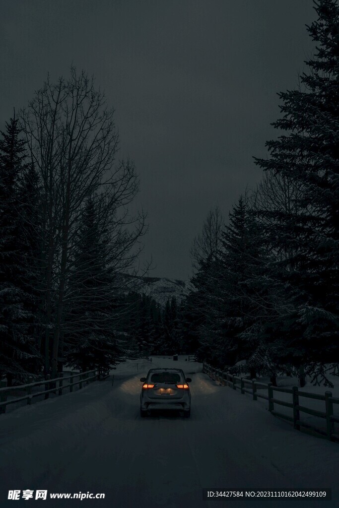 夜幕下在雪道行驶的汽车