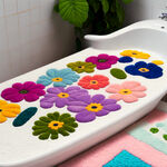 在白色浴缸边上放置一块植绒地垫，图案选用颜色鲜艳可爱花朵，