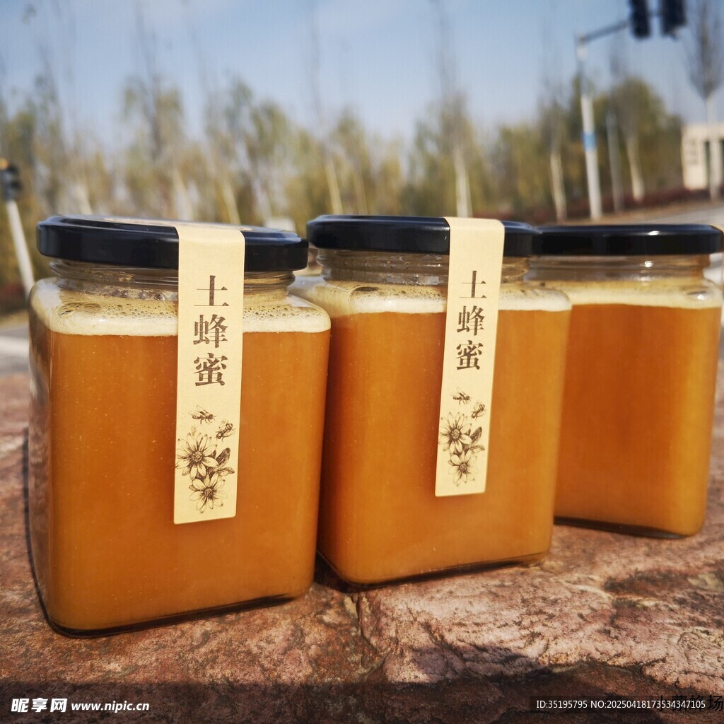 三罐蜂蜜摆放在户外石上