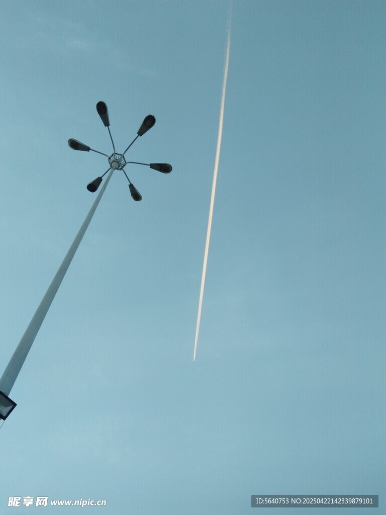 天空中的灯杆与飞机尾迹