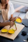 女士专注切芒果于案板上