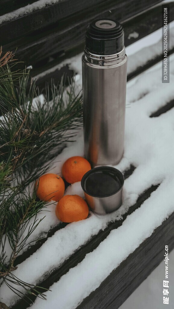 雪地中的保温杯与橘子