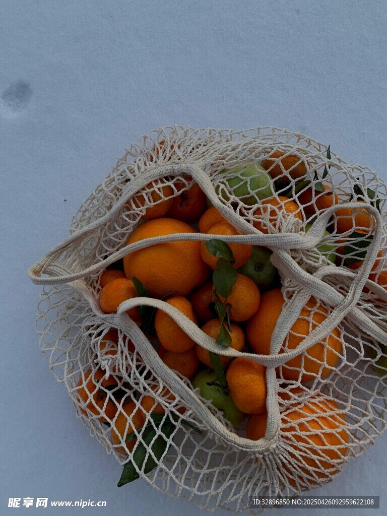 雪地中的网兜装着小橘子