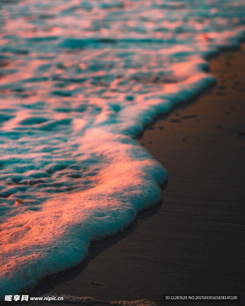 夕阳下的海浪拍打沙滩