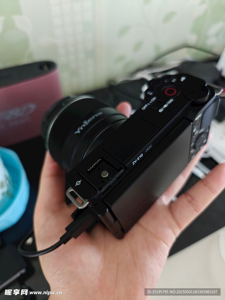 手持黑色相机及充电线