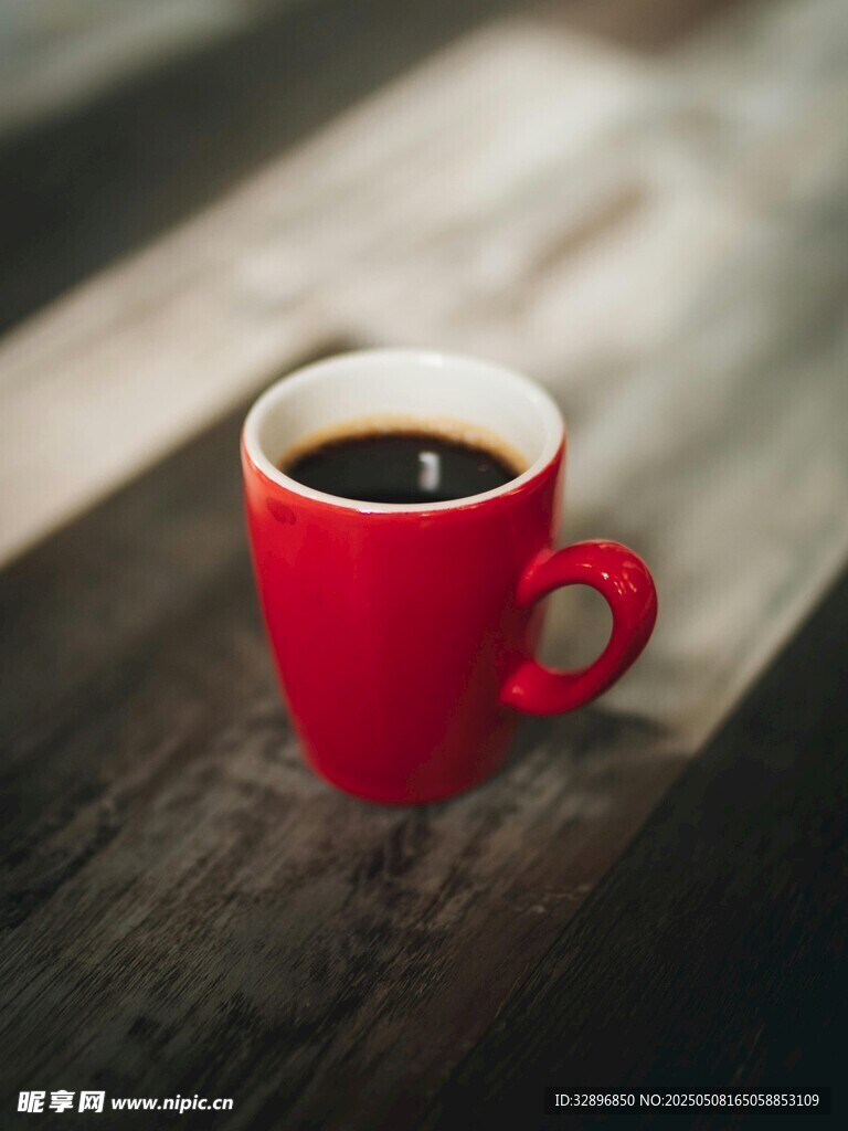 红色咖啡杯置于木质桌面