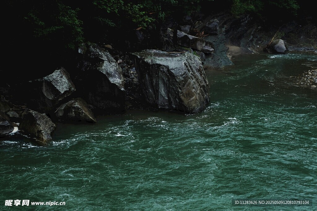 碧绿河水旁的嶙峋岩石