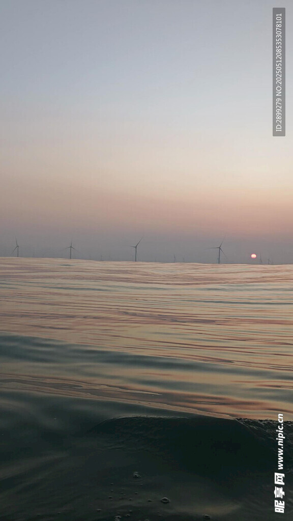 海边日落时分的平静海面风车塔