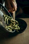 筷子翻炒锅中的绿色蔬菜
