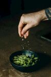手撒调料于盘中青豆上